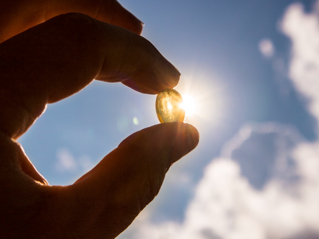 vitamin d supplement held against the sun