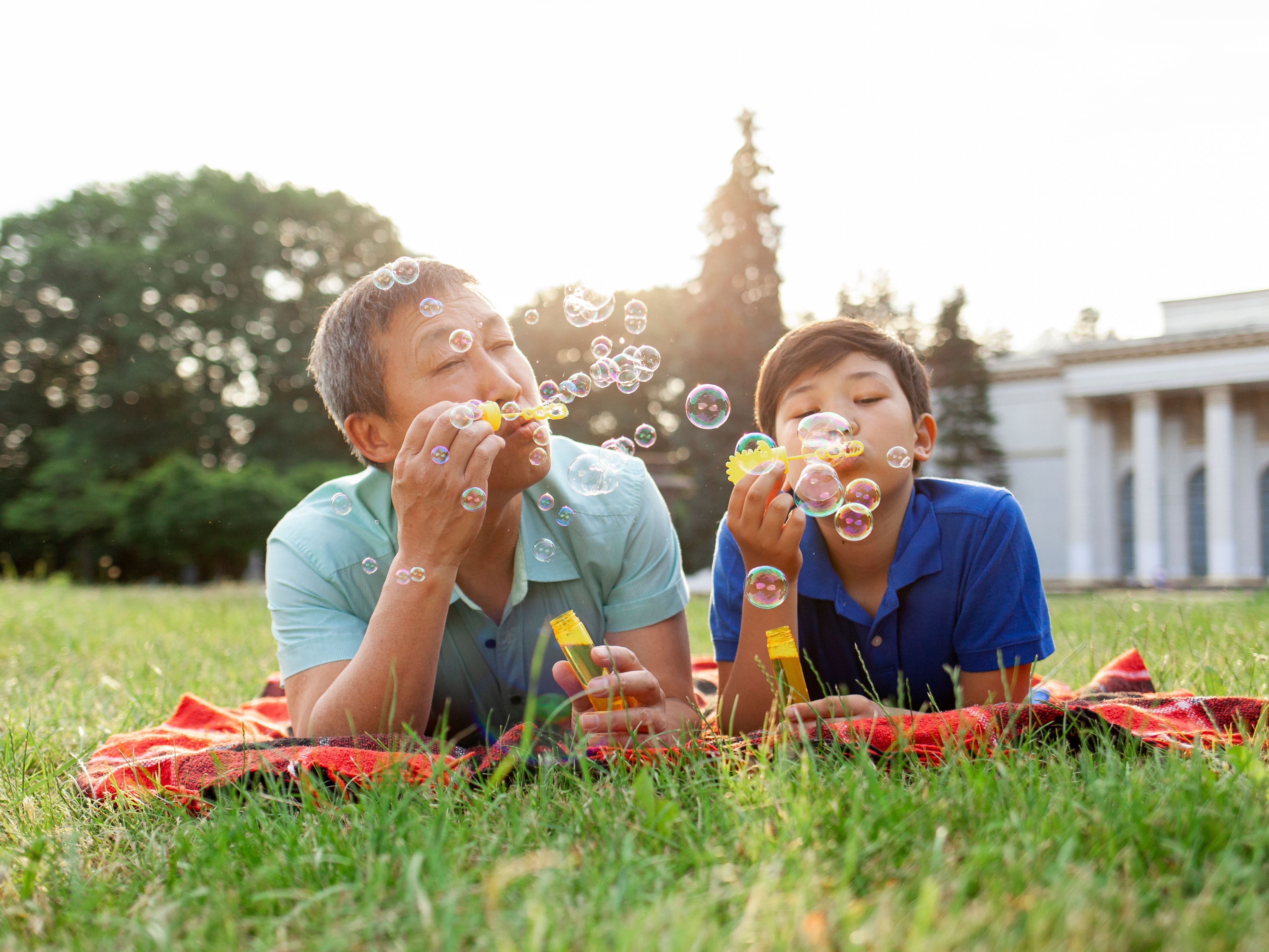 father and son blowing bubbles in grass